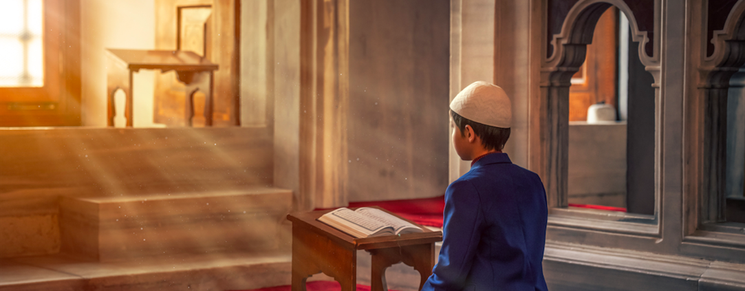 young boy praying the quran during ramadan