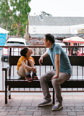 Aspergers syndrome affected boy is sitting on the bench with his father