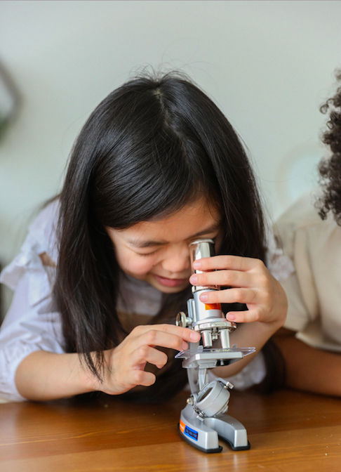 girl looking though a microscope